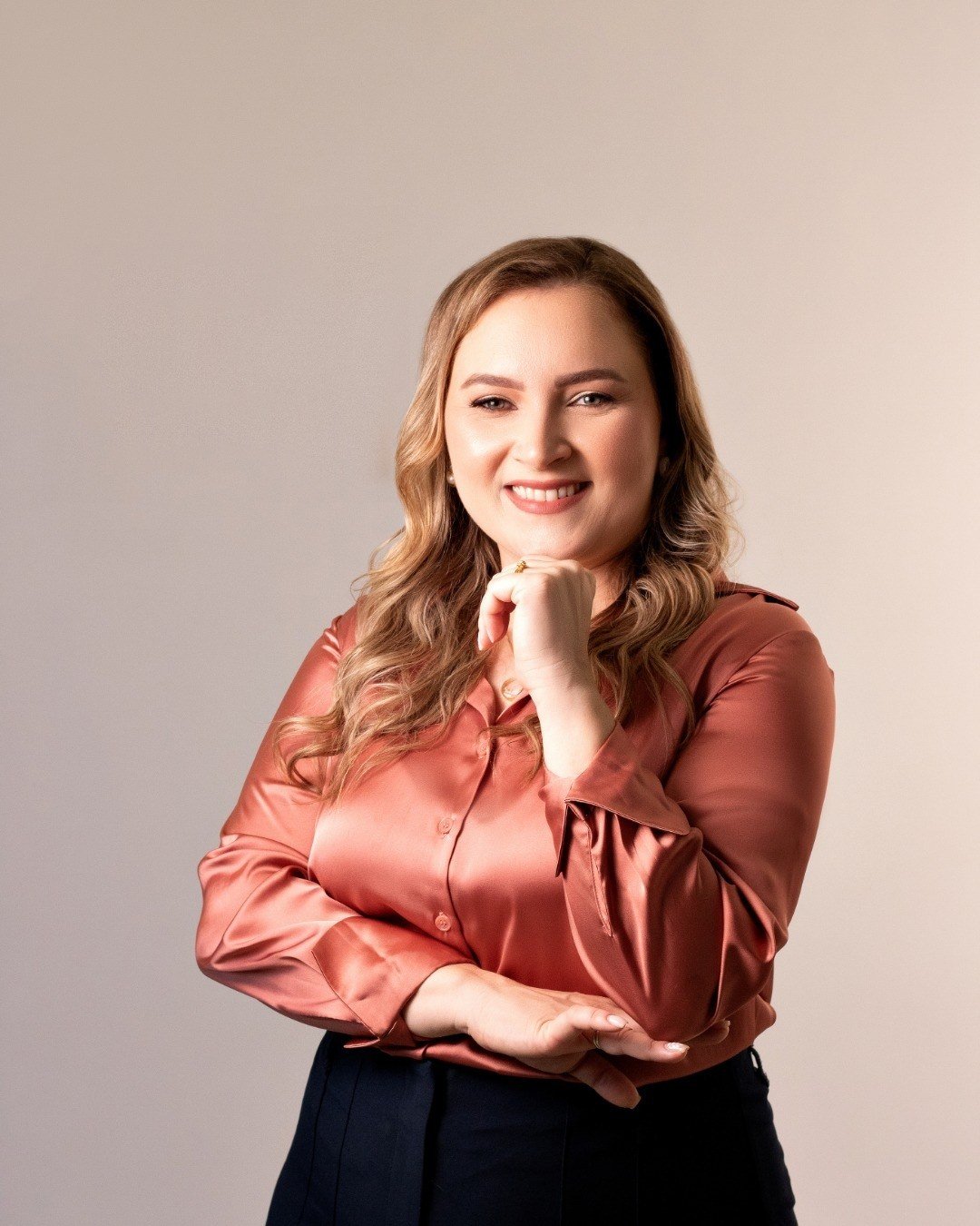 Thaís Melo sorrindo, com a mão apoiada no queixo