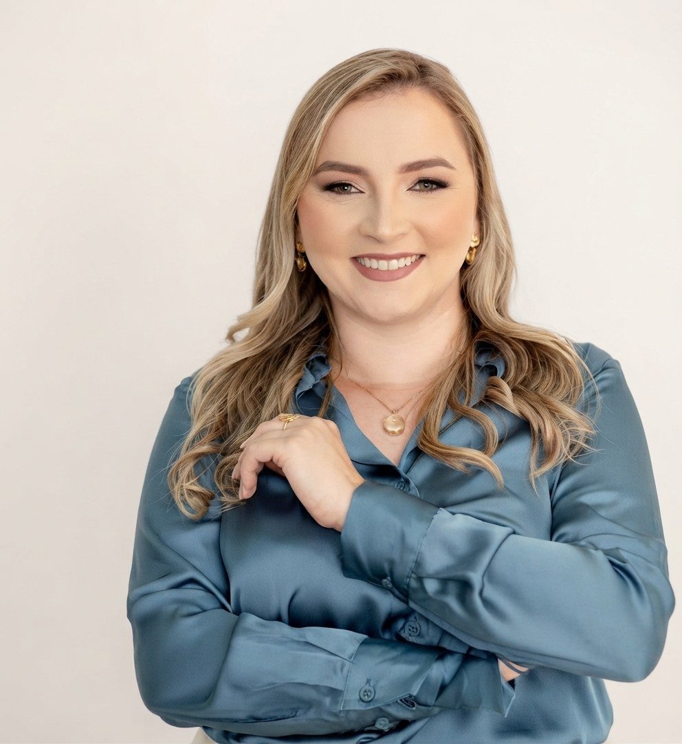 Thaís Melo sorrindo, de blusa azul, com os braços cruzados